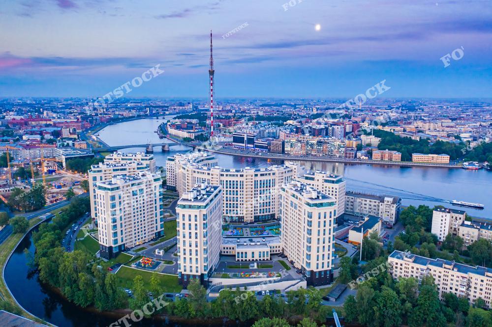 На этой фотографии запечатлен величественный Троицкий собор в Санкт-Петербурге. Собор привлекает внимание своими монументальными размерами, классическим стилем архитектуры и голубыми куполами с звёздами. Снимок сделан с высоты, что позволяет оценить великолепие здания и его гармонию с окружающей городской застройкой. Видны прилегающие улицы, здания, автомобили и ухоженные зелёные насаждения. Изображение идеально подходит для использования в культурно-исторических публикациях, туристических буклетах, образовательных материалах и как часть фотогалереи Санкт-Петербурга.